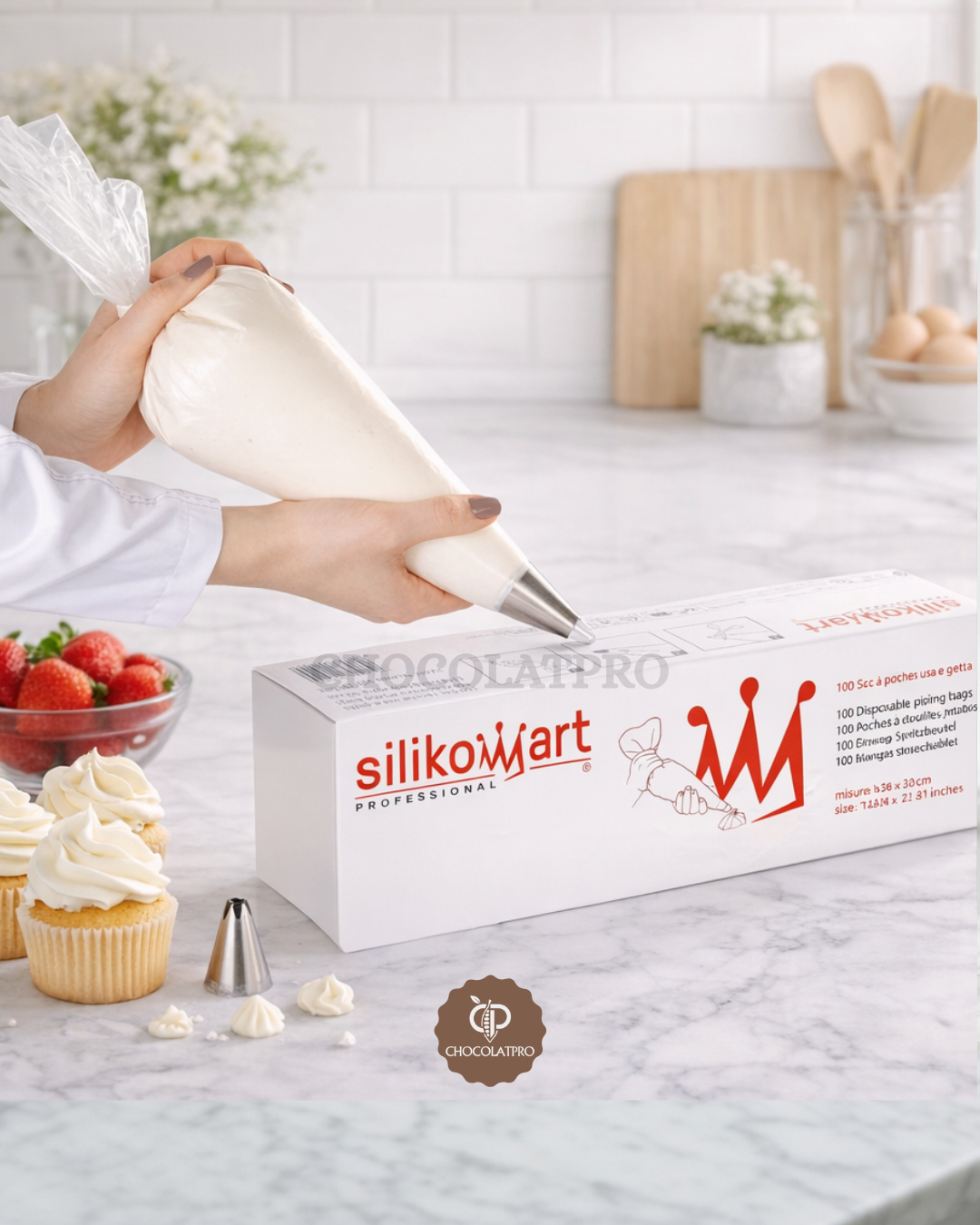 Silikomart professional piping bag set on a kitchen counter with cupcakes and strawberries.